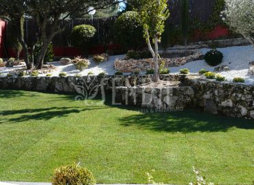 Diseño paisajístico con bancales de piedra, grava blanca y césped
