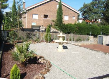 Diseño paisajístico de entrada con grava decorativa y fuente ornamental