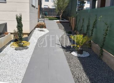 Diseño de pasillo ajardinado con grava blanca, palmera y recorrido central