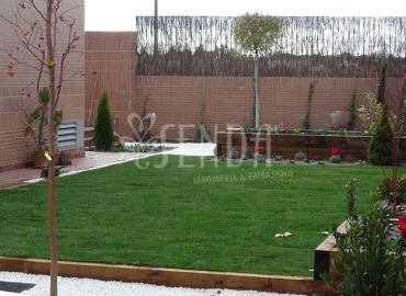 Lateral ajardinado con pradera, arbolado joven y zona estructurada