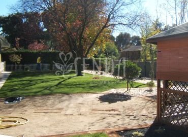 Un lateral ajardinado que combina pradera, arbolado y zona auxiliar